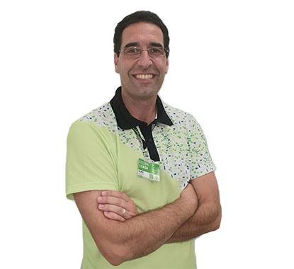 Diretor da loja AKI Cascais a sorrir com os braços cruzados e uma camisola verde